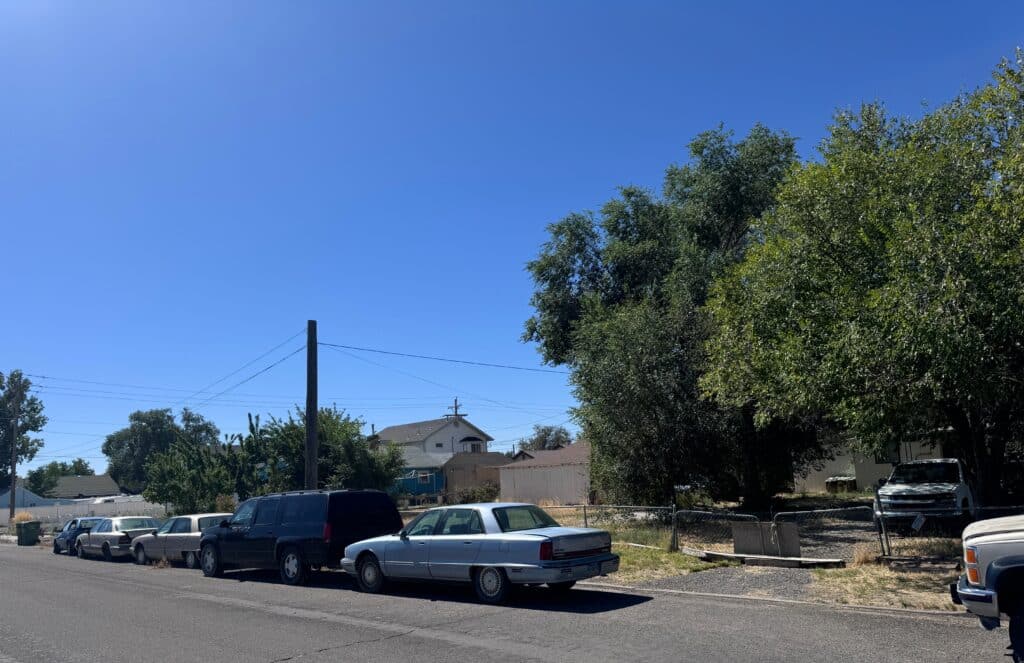 cars not running parked on the street in front of the DA's house and a yard filled with weeds