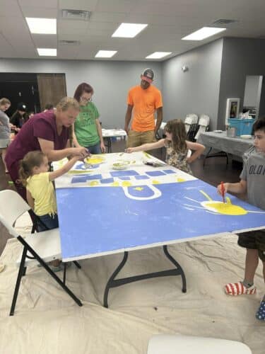 people painting a mural board