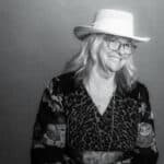 black and white photo of Deb wearing a hat and smiling and dressed up