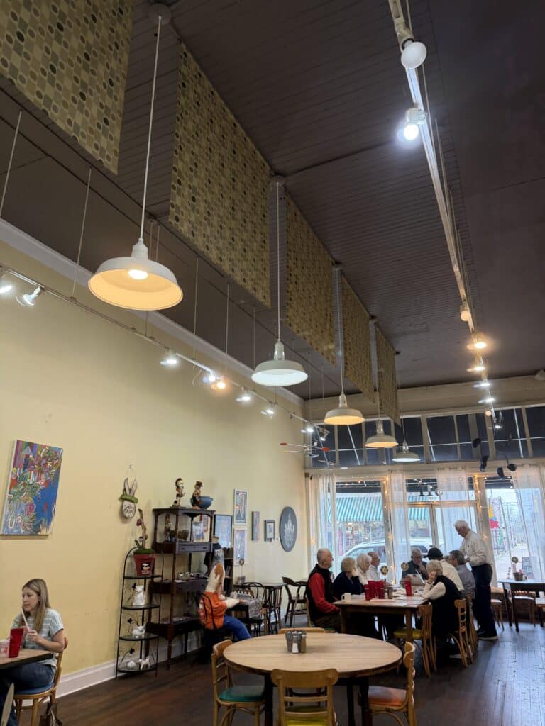 inside of coffee shop in downtown natchez, group ofseniors at a table, big front window, and historic ceilings with tall walls