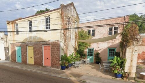 Old building with new paint on the doors and the courtyard has sitting areas and plants - added with AI 