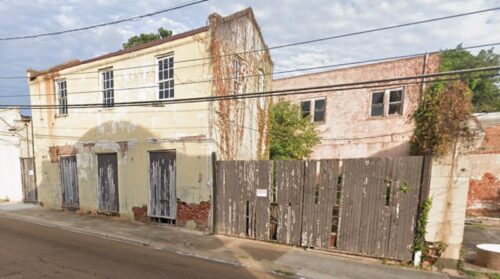 Old beat up building in Natchez MS with a bad fence and empty