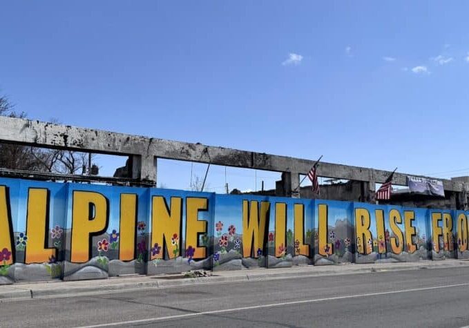 block long burned out buildings in Alpine TX has a mural in front of it that says Alpine will rise