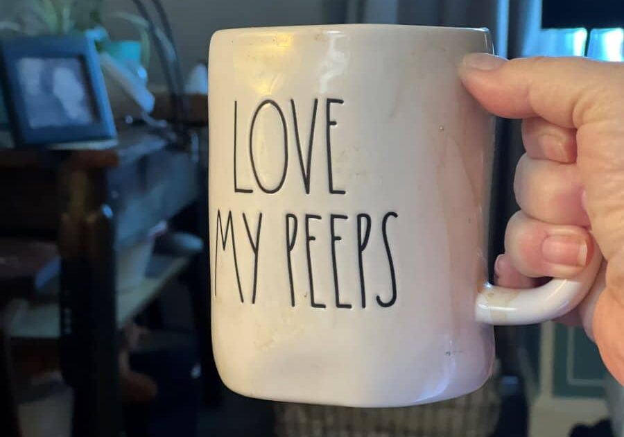 coffee cup with love my peeps written on it held by a white hand