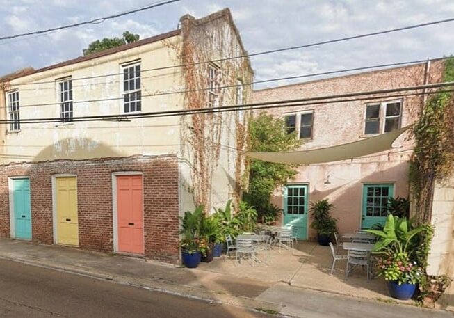 Old building with new paint on the doors and the courtyard has sitting areas and plants - added with AI